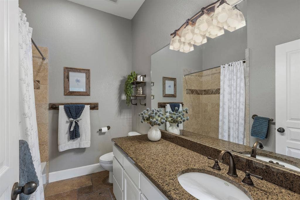 6810 Trinity Falls Parkway, McKinney, TX 75071 Vaulted bathroom ceiling with a tiled shower, single vanity with a solid surface countertop, and large wall-mounted mirror