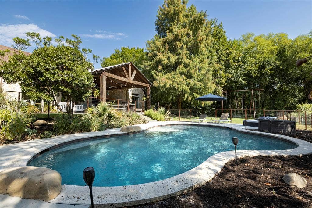 6810 Trinity Falls Parkway, McKinney, TX 75071 Freeform swimming pool with a stone coping and surrounding landscaping