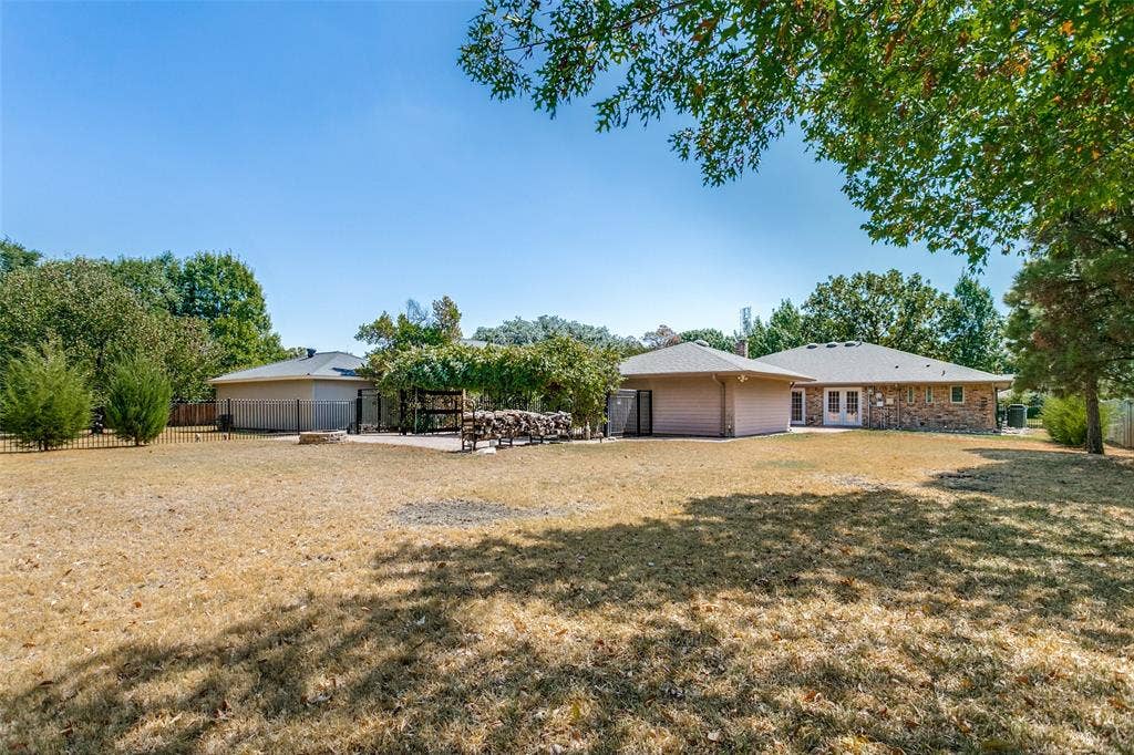 2717 Pinehurst Drive, Plano, TX 75075 Expansive backyard with a large patio area, two sets of French doors, and mature perimeter trees