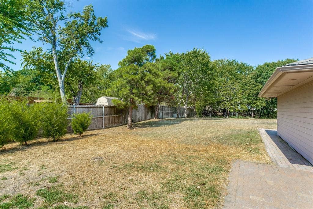 2717 Pinehurst Drive, Plano, TX 75075 Expansive backyard featuring a privacy fence, mature trees, and a paved patio area