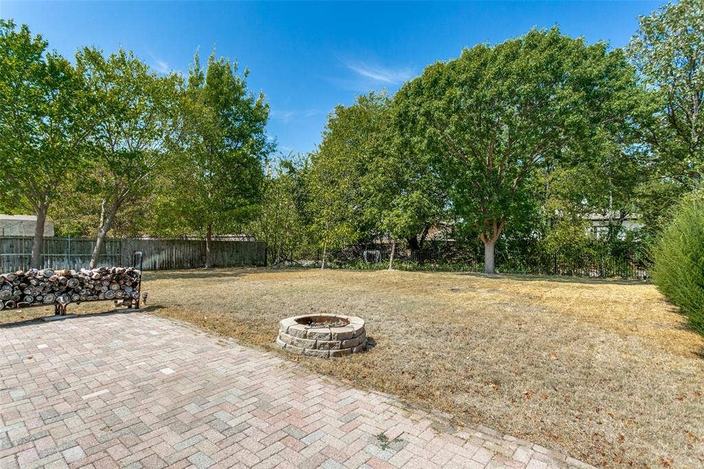 2717 Pinehurst Drive, Plano, TX 75075 Expansive backyard featuring a paver patio, stone fire pit, and mature trees