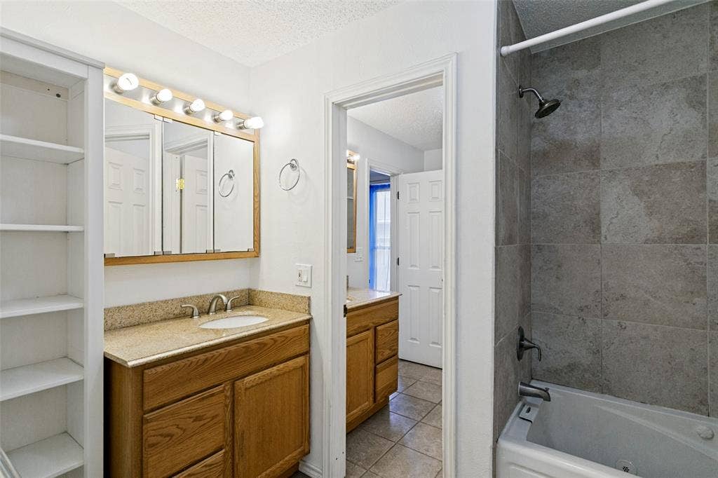 2717 Pinehurst Drive, Plano, TX 75075 Bathroom featuring a built-in vanity with a light-colored countertop, integrated sink, and wood-finish cabinetry