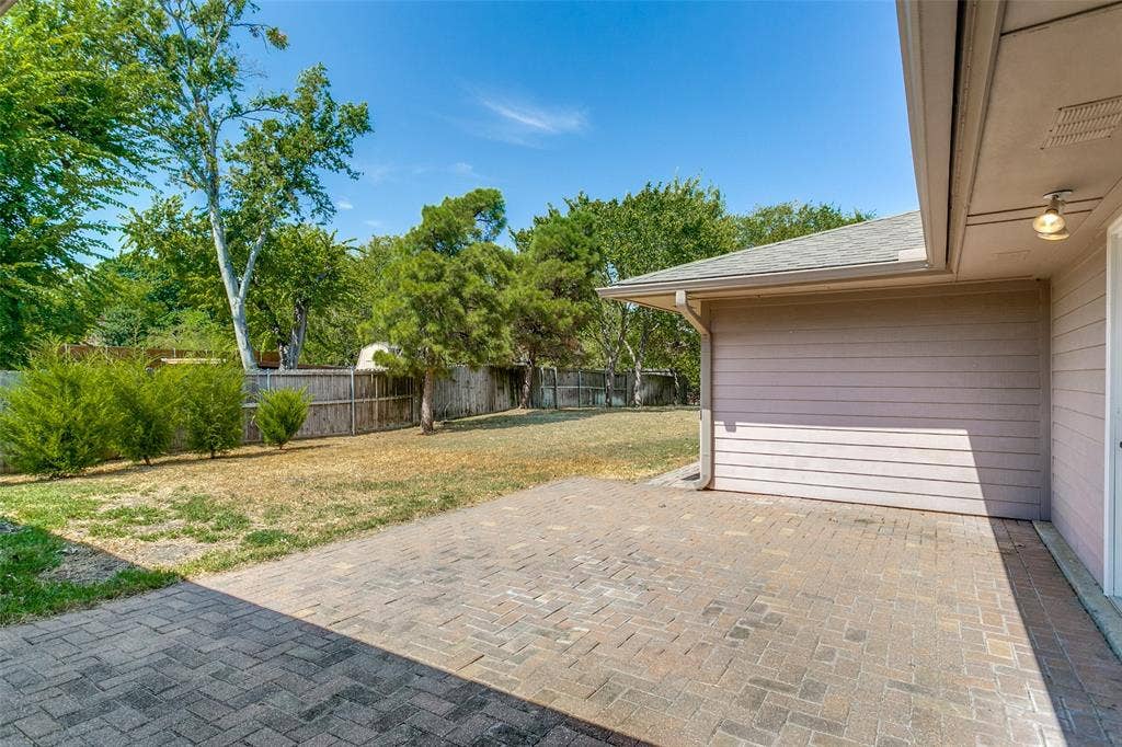 2717 Pinehurst Drive, Plano, TX 75075 Spacious paver patio with a wood privacy fence and mature landscaping