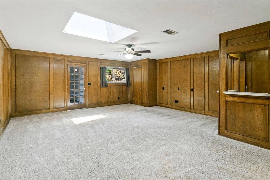 2717 Pinehurst Drive, Plano, TX 75075 Spacious room featuring wood paneling, wall-to-wall carpeting, and a built-in wet bar with a white countertop
