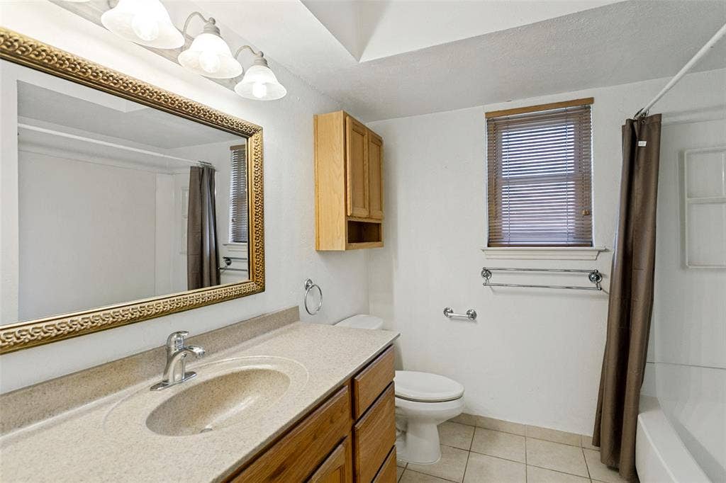 2717 Pinehurst Drive, Plano, TX 75075 Vanity with integrated sink, wood-finish cabinetry, and a large framed mirror