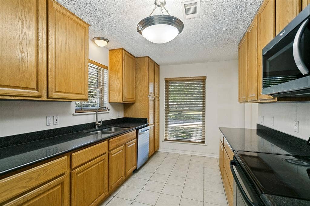 2717 Pinehurst Drive, Plano, TX 75075 Wood cabinetry and dark countertops