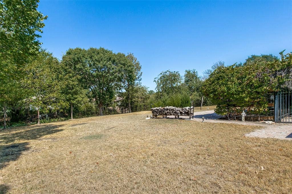 2717 Pinehurst Drive, Plano, TX 75075 Expansive outdoor space featuring mature trees, a clear blue sky, and a paved entrance