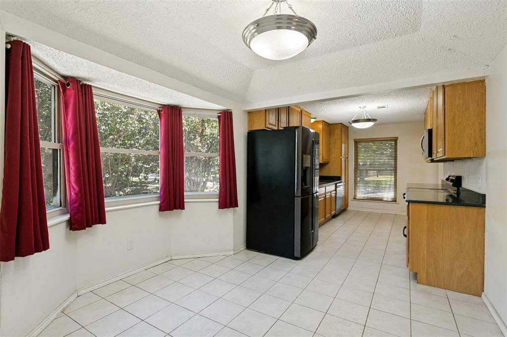 2717 Pinehurst Drive, Plano, TX 75075 Kitchen featuring wood-finish cabinetry, black appliances, black countertops, and a tile floor