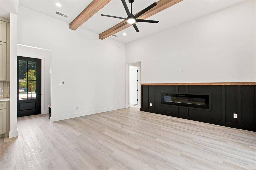 3023 Mallory Drive, Dallas, TX 75216 Vaulted ceilings with exposed wood beams, plank wood-finish flooring, linear electric fireplace, paneled accent wall, and a ceiling fan