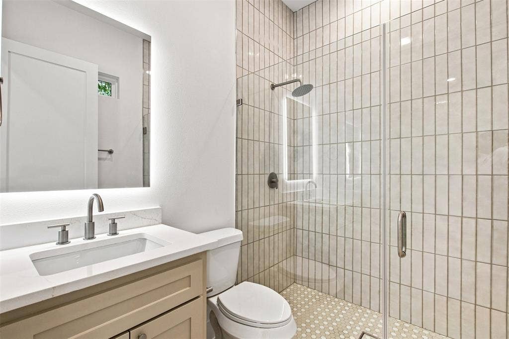 3023 Mallory Drive, Dallas, TX 75216 Vanity with an integrated sink, illuminated mirror, and brushed nickel fixtures