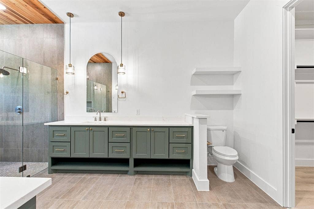 3023 Mallory Drive, Dallas, TX 75216 Spacious bathroom featuring a double vanity with green cabinetry, a glass-enclosed shower, a wood-finish ceiling accent, and built-in shelving