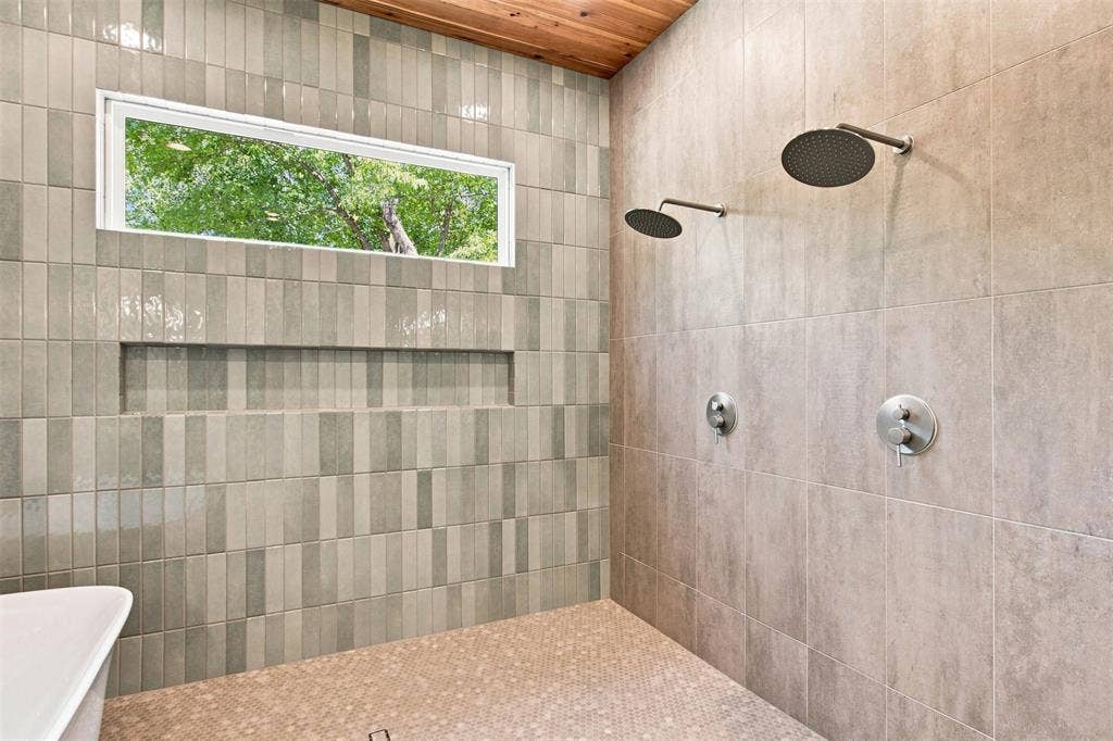 3023 Mallory Drive, Dallas, TX 75216 Dual rain shower heads with brushed nickel fixtures, a built-in shower niche, and a horizontal transom window