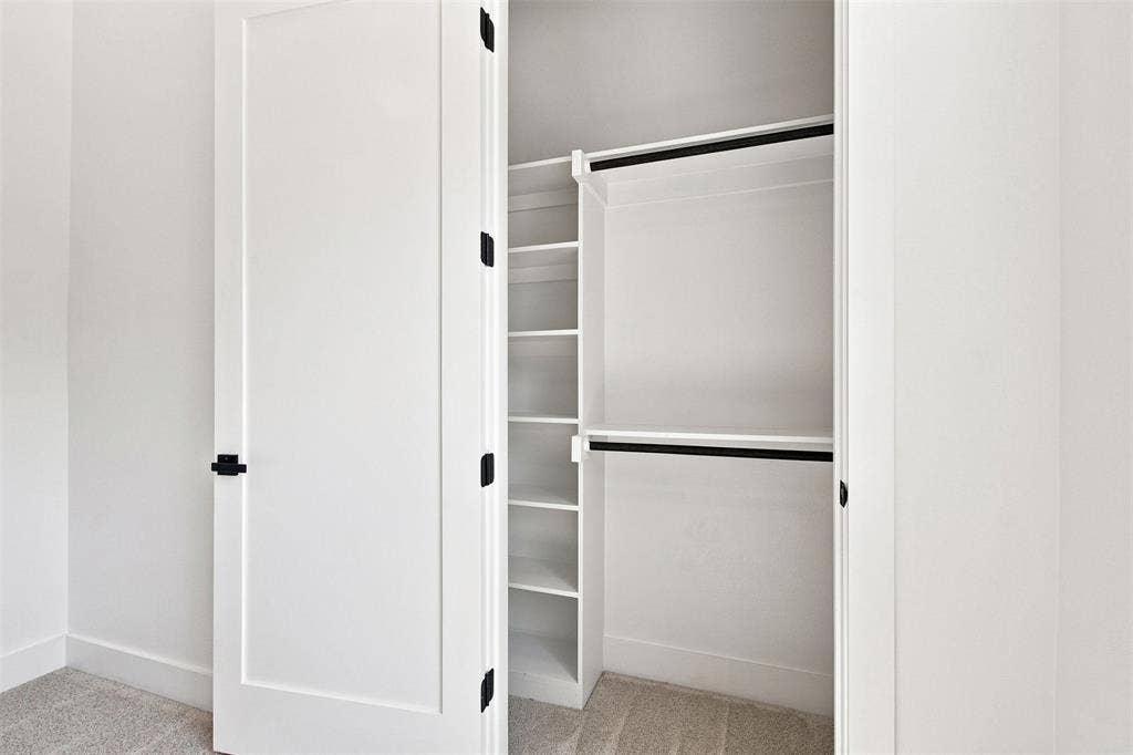 3023 Mallory Drive, Dallas, TX 75216 White closet doors with black hardware, built-in shelving, and dual hanging rods