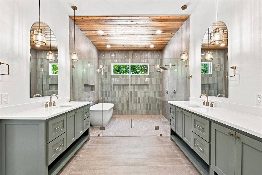 3023 Mallory Drive, Dallas, TX 75216 Dual vanities with white countertops, a freestanding soaking tub, a walk-in shower with glass enclosure, a wood-paneled ceiling, and pendant lighting fixtures