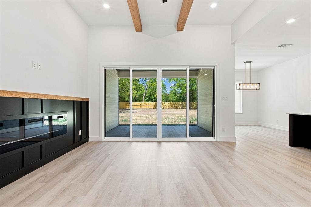 3023 Mallory Drive, Dallas, TX 75216 Vaulted ceiling with wood beams, light wood-finish flooring, built-in fireplace feature with wood mantel, recessed lighting, and sliding glass doors to outdoor patio