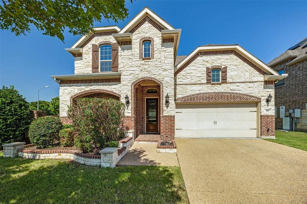801 Feathering Way, Plano, TX 75074 Stone and brick exterior with arched entryways, a two-car garage, and established landscaping