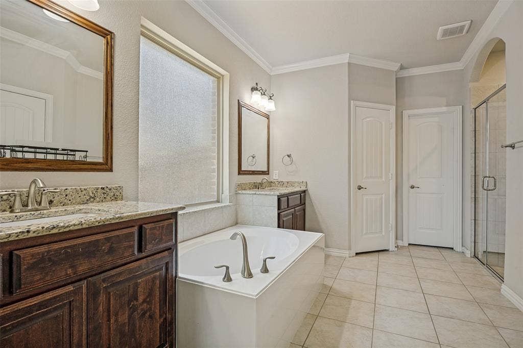 801 Feathering Way, Plano, TX 75074 Dual vanity with granite countertops, a built-in soaking tub, a separate glass-enclosed shower, and tile flooring