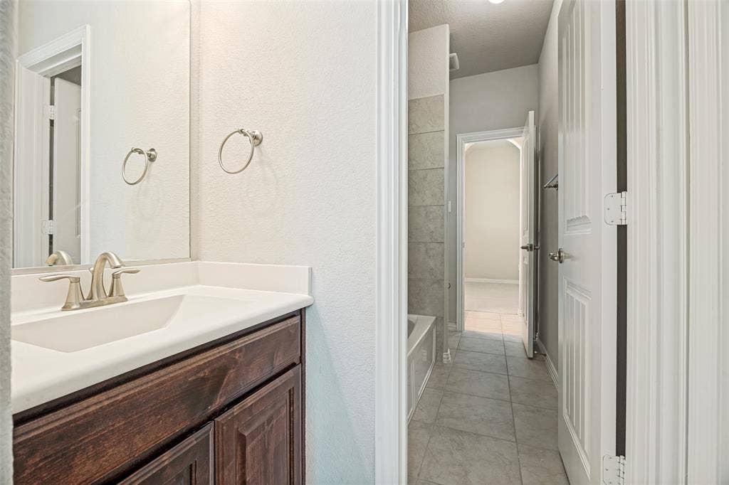 801 Feathering Way, Plano, TX 75074 Wood-finish vanity with a white countertop and undermount sink
