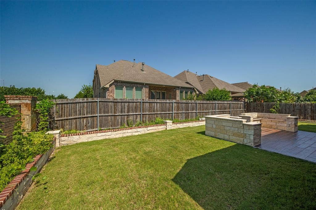 801 Feathering Way, Plano, TX 75074 Expansive backyard featuring a stone patio, built-in stone seating, and a dedicated fire pit area