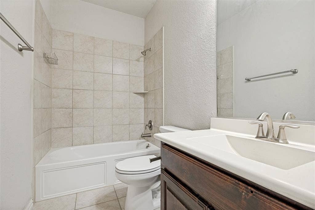 801 Feathering Way, Plano, TX 75074 White bathtub with tile surround, a built-in shelf, and a shower fixture