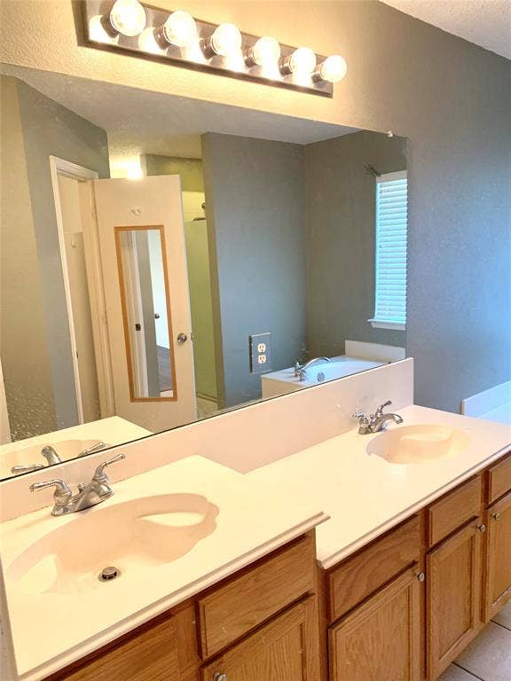 5512 Vineyard Lane, McKinney, TX 75070 Dual vanity with white countertops, integrated sinks, and wood-finish cabinetry