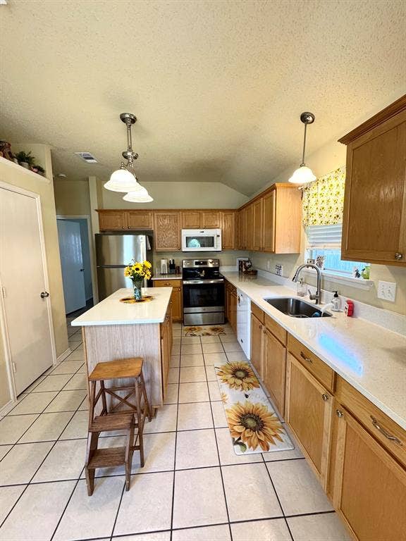5512 Vineyard Lane, McKinney, TX 75070 Kitchen featuring a central island with white countertop, extensive light wood cabinetry, stainless steel appliances, and white tile flooring