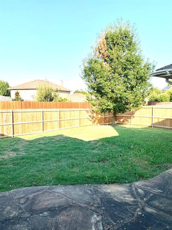 5512 Vineyard Lane, McKinney, TX 75070 Expansive backyard featuring a natural wood fence, mature tree, and a flagstone patio