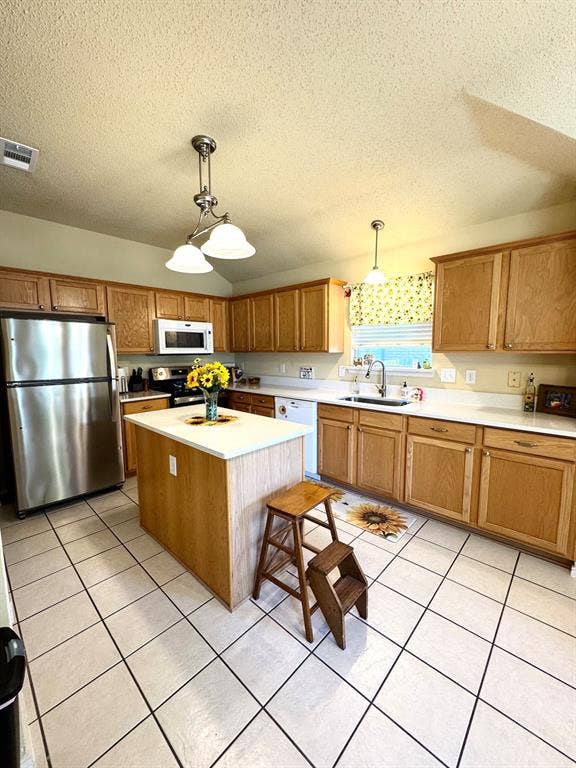5512 Vineyard Lane, McKinney, TX 75070 Kitchen featuring wood cabinetry, stainless steel appliances, a center island with a light-toned countertop, and tile flooring