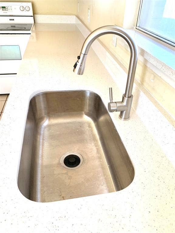 5512 Vineyard Lane, McKinney, TX 75070 Stainless steel undermount sink, solid surface countertop, contemporary brushed nickel faucet, integrated spray nozzle, and white electric range