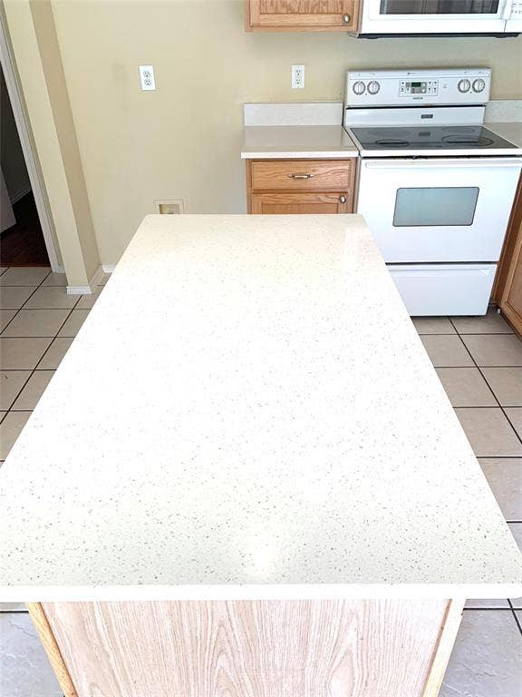 5512 Vineyard Lane, McKinney, TX 75070 Kitchen island with a light-toned countertop, wood-finish base, tile flooring, and a white electric range
