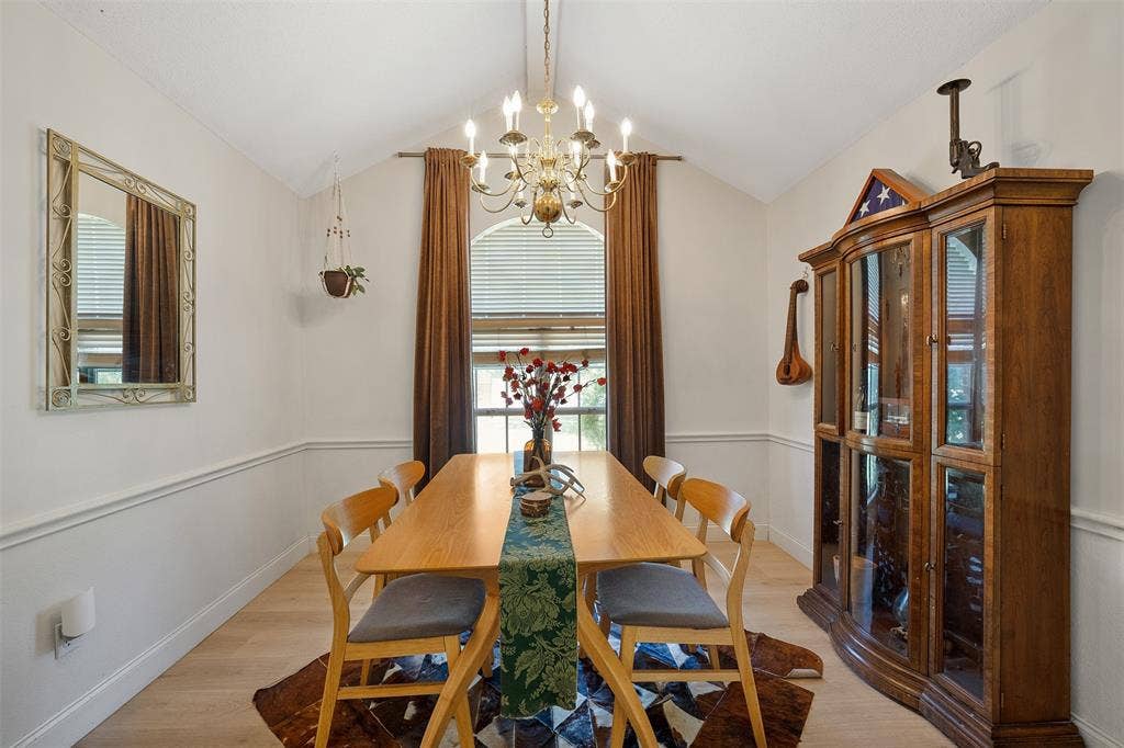 310 Linda Lane, Lindale, TX 75771 Vaulted ceiling with an ornate chandelier, arched window with blinds, chair rail molding, and wood-finish flooring
