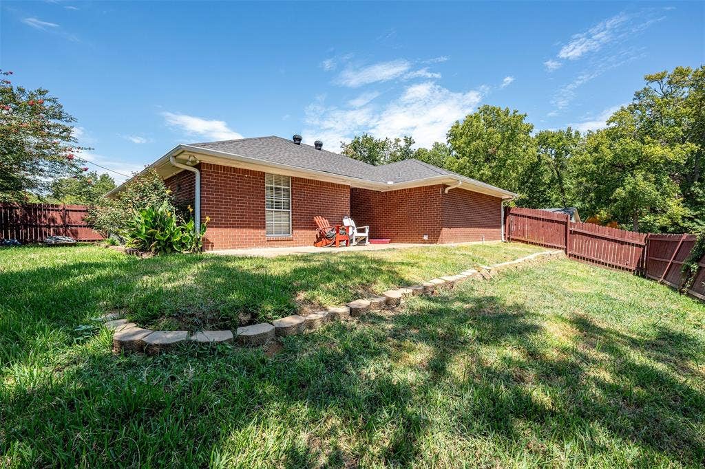 310 Linda Lane, Lindale, TX 75771 Brick exterior, dark shingle roof, white trim, privacy fencing, and a concrete patio