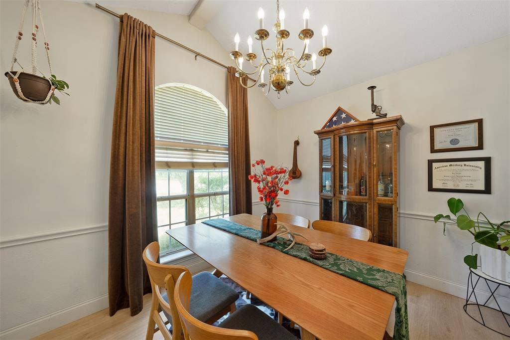 310 Linda Lane, Lindale, TX 75771 Vaulted ceiling, arched window with blinds, decorative chair rail molding, wood-finish flooring, and a brass chandelier
