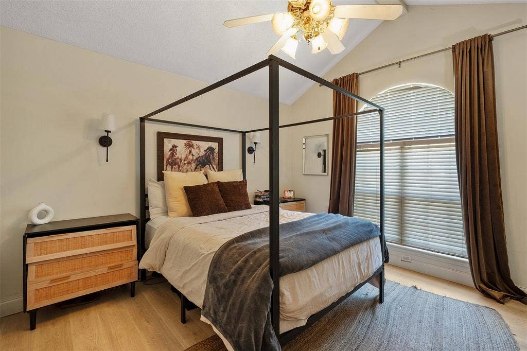 310 Linda Lane, Lindale, TX 75771 Vaulted ceiling, arched window with blinds, wood-finish flooring, two wall sconces, and a ceiling fan with light fixture