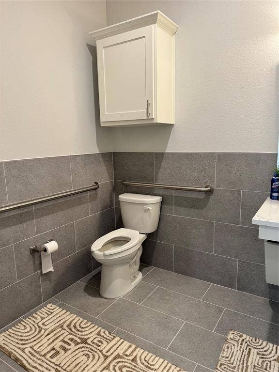 1630 W Prosper Trail, #930, Prosper, TX 75078 Recessed wall cabinet, white toilet, tile flooring, and wall-mounted grab bars