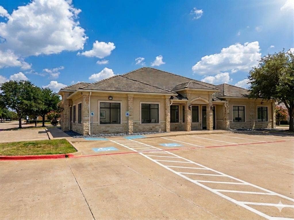 4512 Legacy Drive, #100, Plano, TX 75024 Stone facade building with a multi-gabled roofline, multiple windows, and a dedicated parking area with accessible spaces