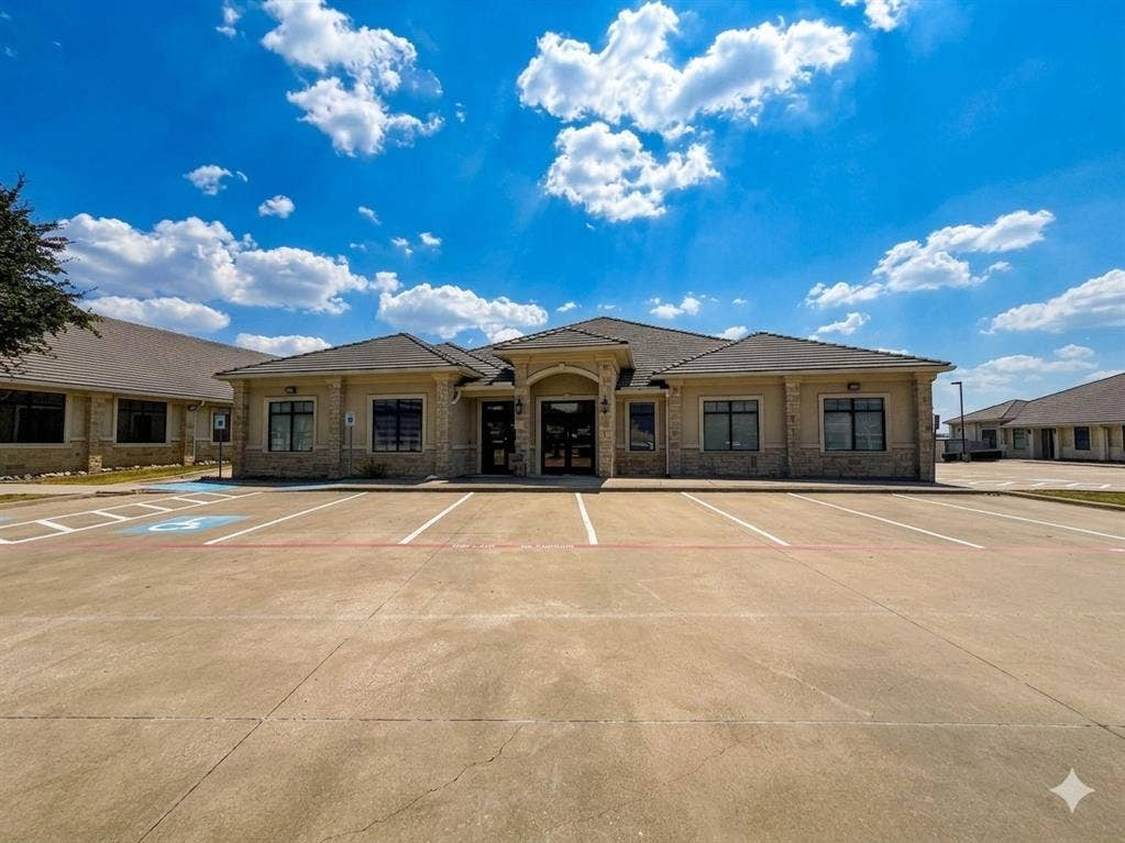 4512 Legacy Drive, #100, Plano, TX 75024 Contemporary commercial building featuring a stone and stucco exterior, dark-framed windows, and a large paved parking area