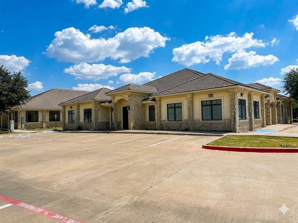 4512 Legacy Drive, #100, Plano, TX 75024 Stucco and stone facade, tile roofing, multiple windows, and a large paved parking lot