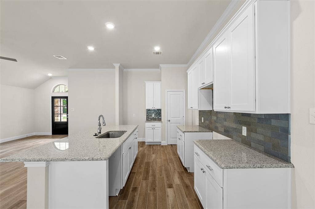Kitchen featuring white cabinetry, light-toned countertops, subway tile backsplash, and wood-finish flooring