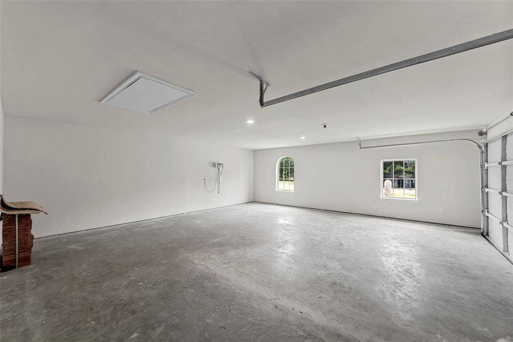 Spacious garage with concrete flooring, recessed lighting, and two windows providing natural illumination