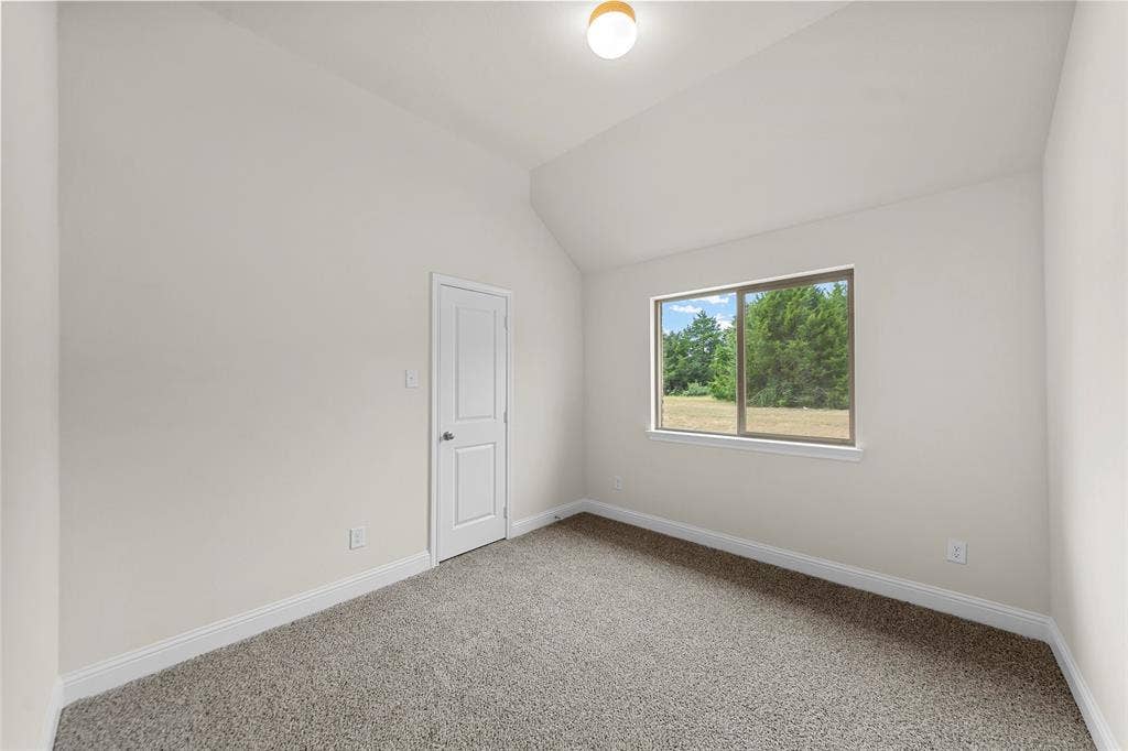 Vaulted ceiling, neutral wall paint, light-colored carpet, rectangular window, and a single ceiling-mounted light fixture