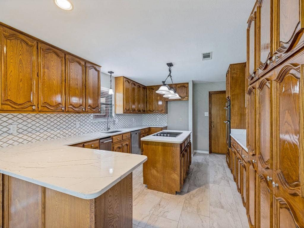 26 Lago Vista W, Wylie, TX 75098 Kitchen featuring extensive cabinetry, Quartz counters, tile backsplash, and a central island with a cooktop