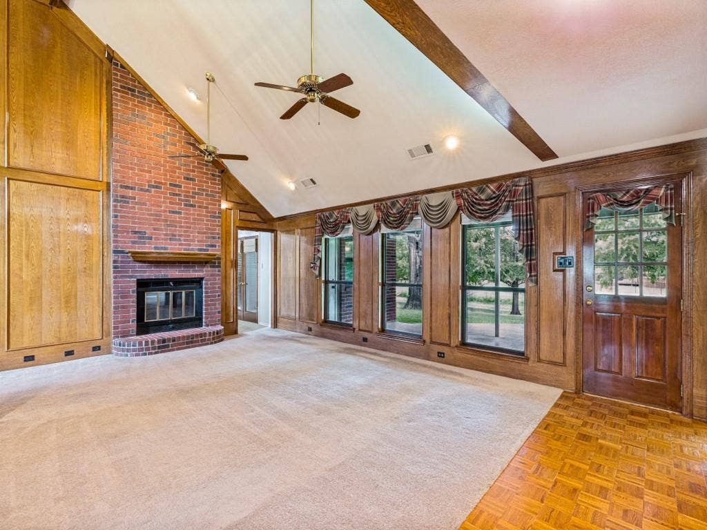 26 Lago Vista W, Wylie, TX 75098 Vaulted ceiling with brick fireplace with wood mantle, wood-paneled walls, multiple windows, and wood-finish flooring
