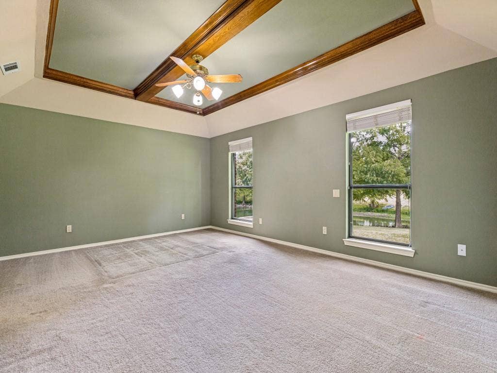 26 Lago Vista W, Wylie, TX 75098 Tray ceiling with wood-finish beams, ceiling fan with integrated lighting, windows looking over back yard and pond.