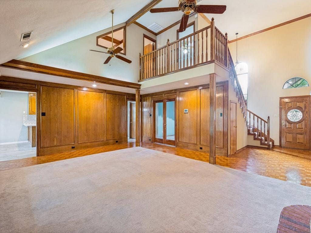 26 Lago Vista W, Wylie, TX 75098 Vaulted ceilings with wood-paneled walls, a second-story interior balcony, and a wood entry door with decorative glass