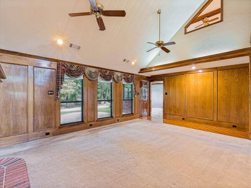 26 Lago Vista W, Wylie, TX 75098 Vaulted ceiling with brick fireplace with wood mantle, wood-paneled walls, multiple windows, carpet and wood-finish flooring