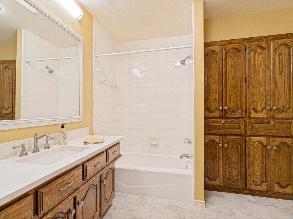 26 Lago Vista W, Wylie, TX 75098 Secondary bath with quartz countertop and integrated sink, chrome-finish faucet, tub/shower combo and wood-finish cabinetry