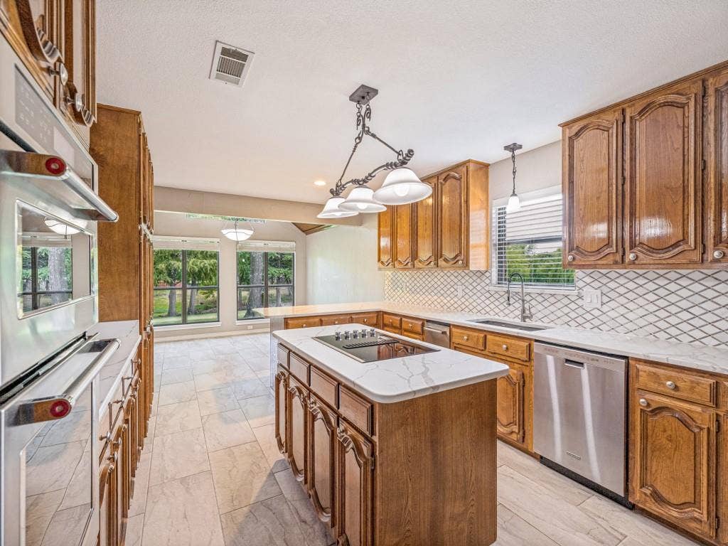 26 Lago Vista W, Wylie, TX 75098 Kitchen featuring wood cabinetry, KitchenAid stainless steel appliances, Quartz counters, a tiled backsplash.
