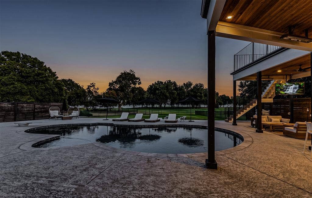 28 Victoria Drive, Rowlett, TX 75088 Freeform swimming pool with a stone coping, expansive stamped concrete patio, and an upper-level balcony with metal railings