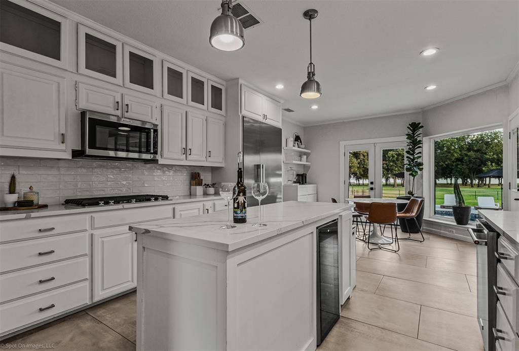 28 Victoria Drive, Rowlett, TX 75088 Kitchen featuring white cabinetry, stainless steel appliances, a center island with integrated beverage cooler, and light-colored tile flooring